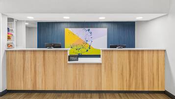 Ein moderner Hotelrezeptionstresen mit Holzverkleidung und einem großen abstrakten Kunstwerk darüber.