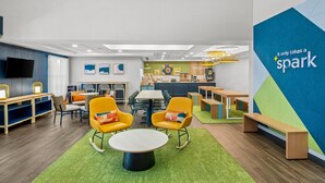 A modern lounge area with seating, a kitchen, and a large wall with the text "it only takes a spark". - Spark by Hilton North Little Rock (North Little Rock)