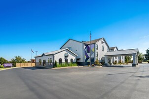 A modern building with a large mural, a parking lot, and a flag.