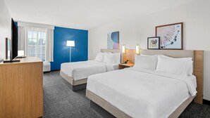 A hotel room with two beds, a desk, a TV, a window with curtains, and artwork on the wall. - Spark by Hilton North Little Rock (North Little Rock)