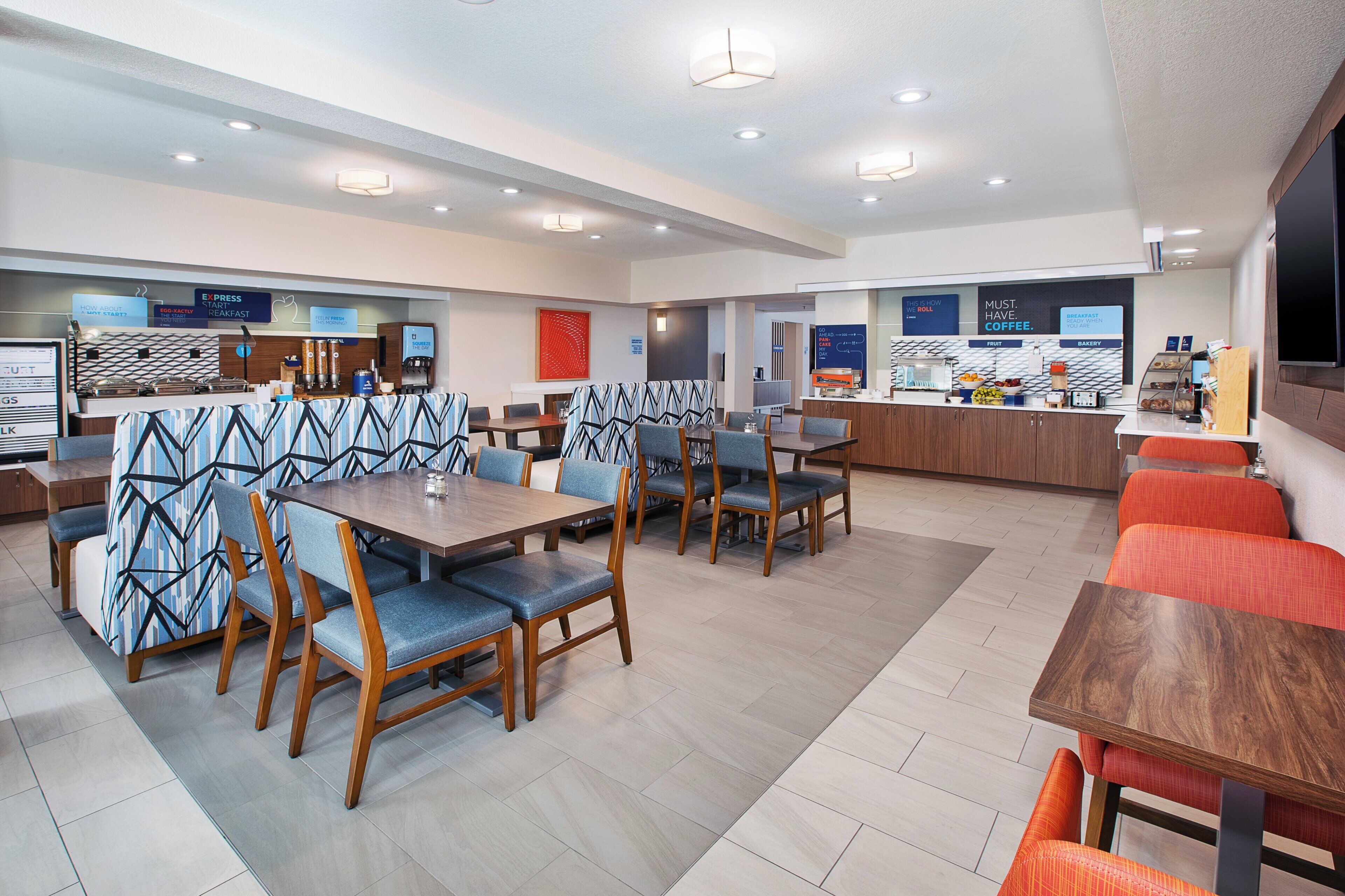 A modern restaurant with multiple dining areas, including booths and tables.