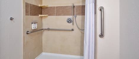 A shower area with a grab bar, a handheld showerhead, and a shower curtain.