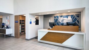 A reception area with a wooden reception desk, a HP monitor, and a sign for the press shop. - Holiday Inn Express Silver City by IHG (Silver City)