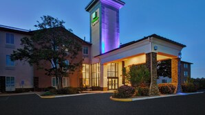 A hotel with a prominent tower featuring a green sign, large windows, and a well-lit entrance. - Holiday Inn Express Silver City by IHG (Silver City)