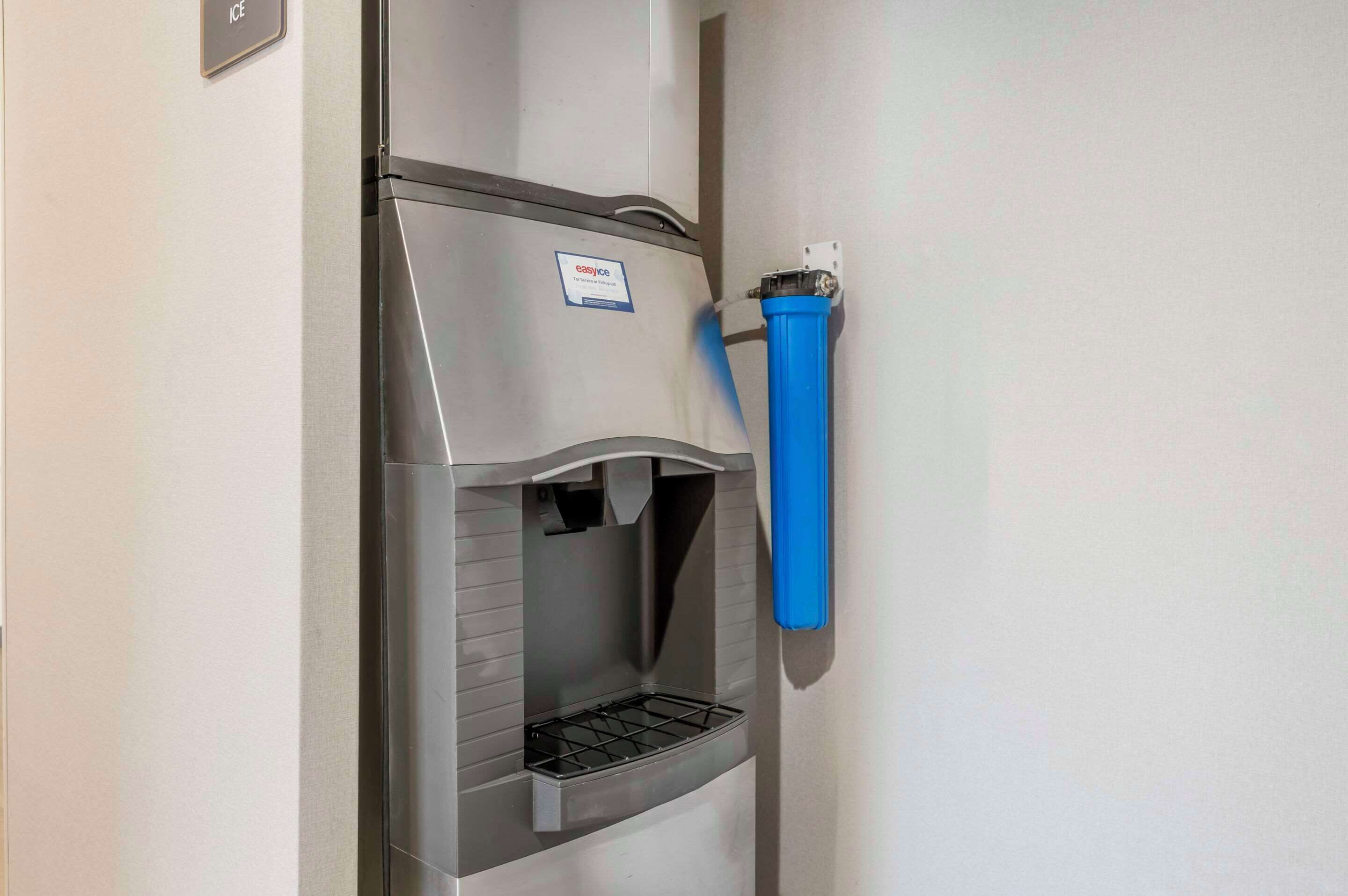 A water dispenser with a blue hose attached to a wall.