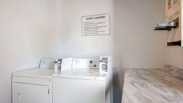 A guest laundry area with two Whirlpool washers and dryers, a sign with laundry instructions, and a marble countertop.