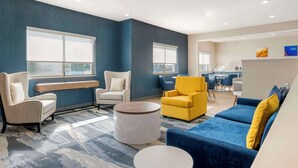 Un hall d’hôtel moderne, doté d’espaces aménagés avec des sièges, d’un comptoir de réception et offrant une vue sur la salle à manger.