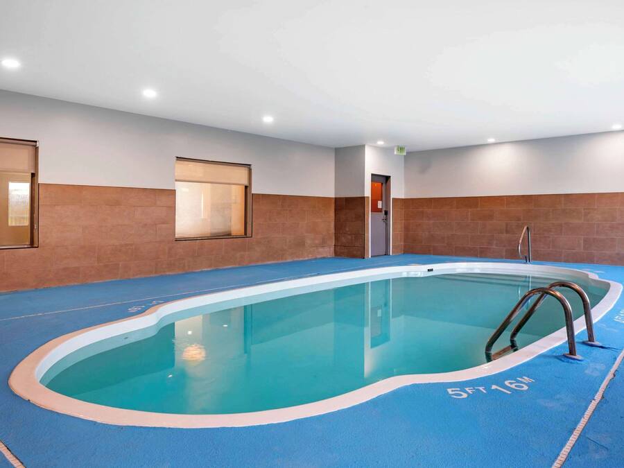 Une piscine intérieure à l’eau d’un bleu cristallin, entourée d’un sol bleu et de murs bruns.