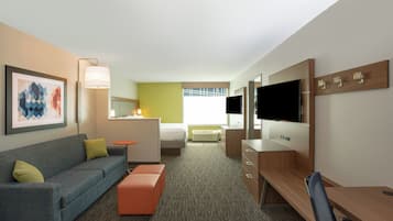 Une chambre d’hôtel avec un canapé, une petite table, une télévision et un bureau.