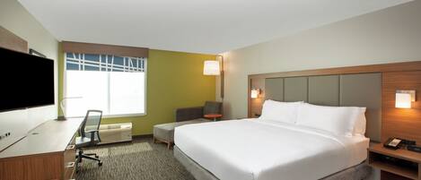 Una habitación de hotel con cama, escritorio, silla y televisor.
