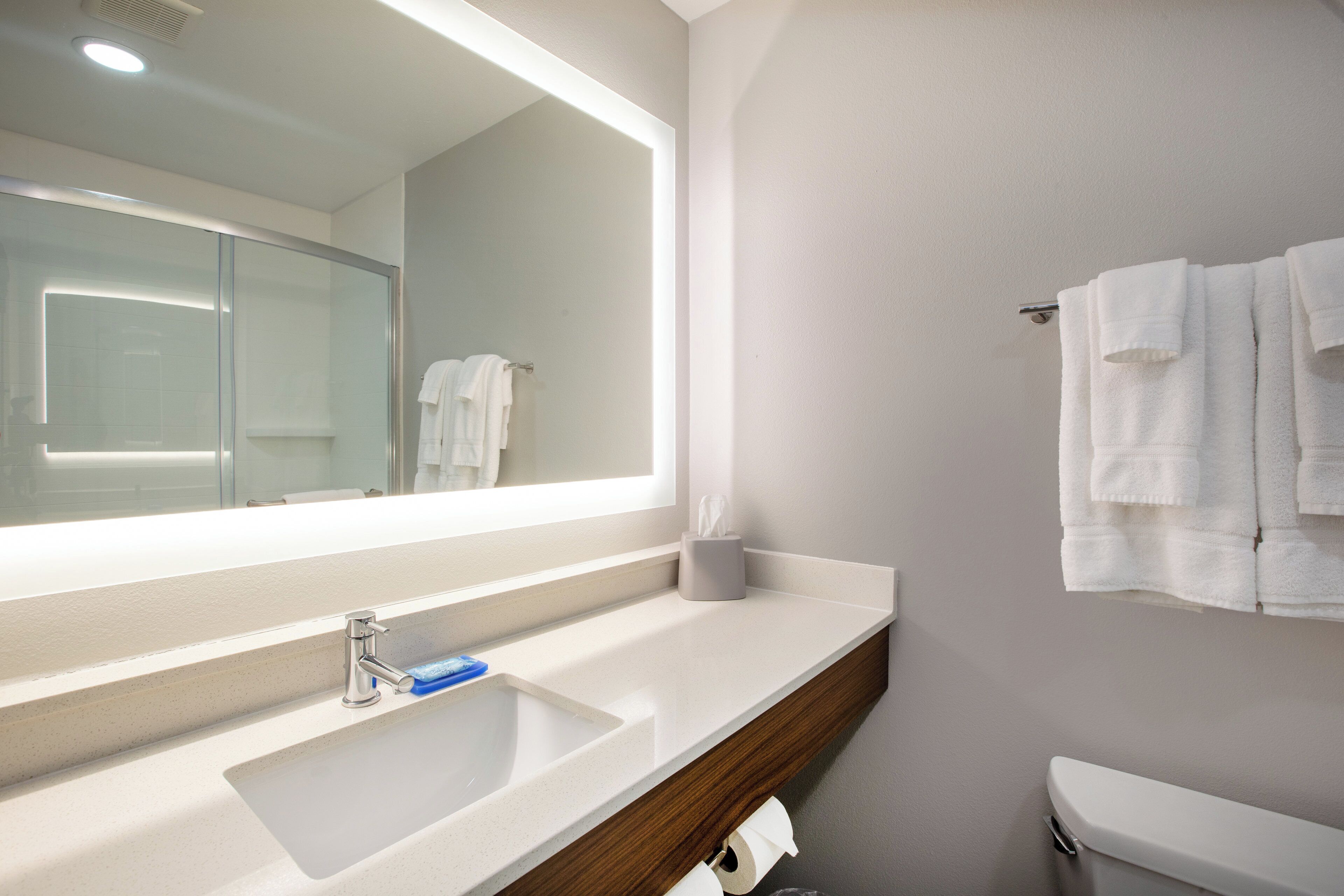 A bathroom with a mirror, sink, and toilet.