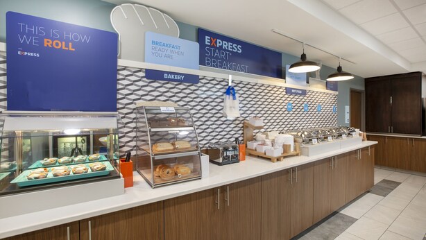 A breakfast buffet area with a sign indicating 'Express Start Breakfast' and a display of pastries and bread.