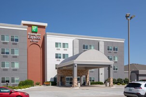 Un edificio de Holiday Inn Express & Suites con fachada de piedra, ventanas amplias y entrada cubierta.