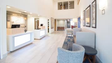 Un hall d’hôtel comprenant un comptoir d’accueil, un espace salon et un escalier menant à un étage supérieur.