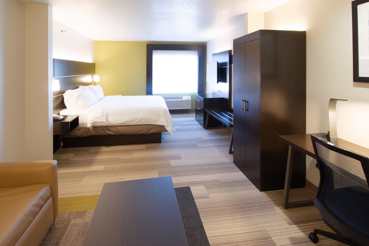 Habitación de hotel con cama, escritorio, armario y un amplio ventanal.