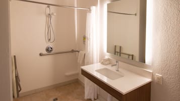 Un baño con ducha, lavabo y espejo.