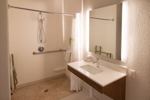 Une salle de bain avec une douche, un lavabo et un miroir.