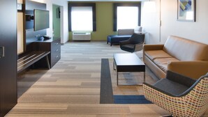 Un salon moderne avec un canapé, un fauteuil et un téléviseur à écran plat fixé au mur.