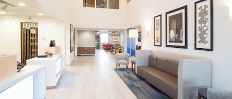 A hotel lobby with a reception desk, seating area, and artwork on the walls.