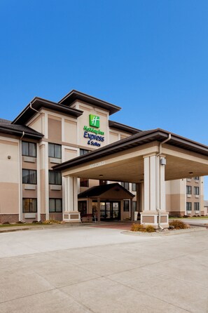 A Holiday Inn Express & Suites building with a covered entrance and a clear blue sky.
