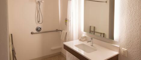 A bathroom with a shower, a sink, and a mirror.