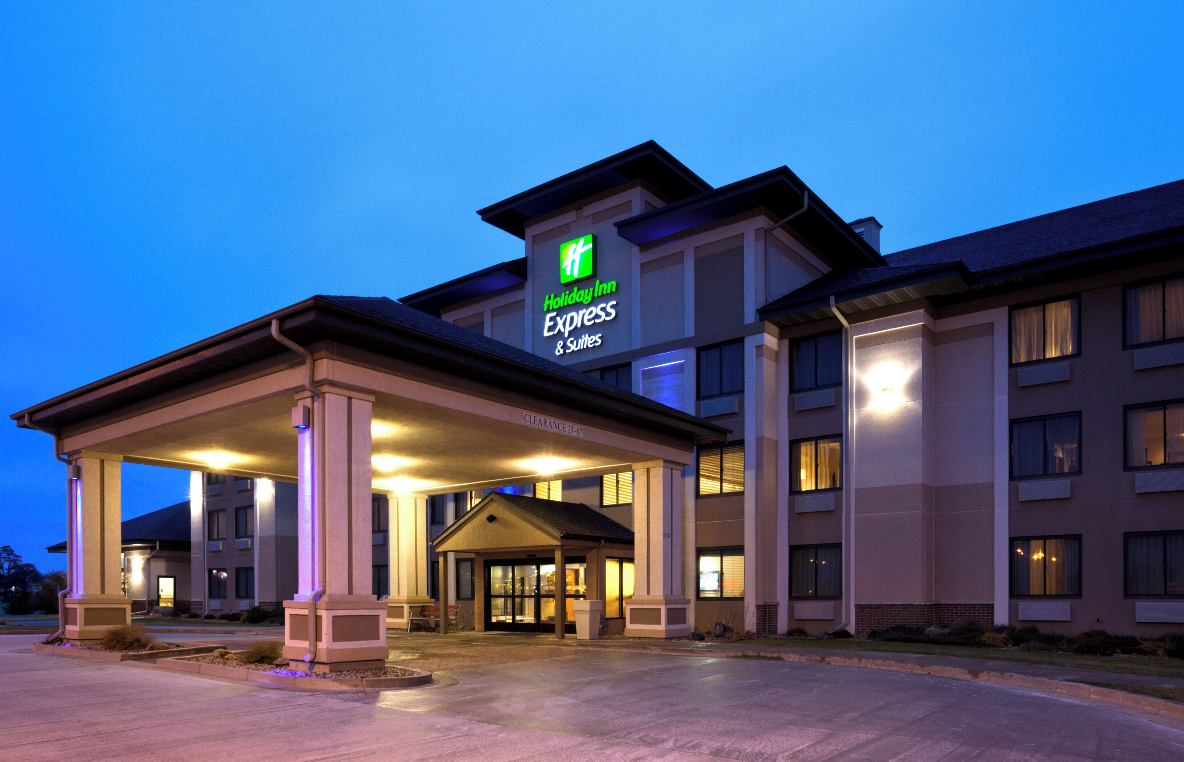 A Holiday Inn Express & Suites building with a covered entrance and a clear sky in the background.