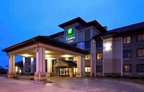A Holiday Inn Express & Suites building with a covered entrance and a clear sky in the background.