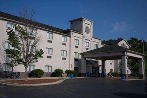 Un hotel con acceso cubierto, múltiples ventanas y una torre del reloj.