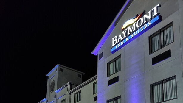 Un hôtel à plusieurs étages, reconnaissable à son grand panneau indiquant « Baymont Inn & Suites ».