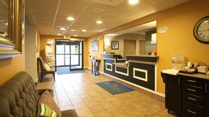 Un hall d’hôtel avec un comptoir d’accueil, une horloge, un tapis bleu et un canapé.