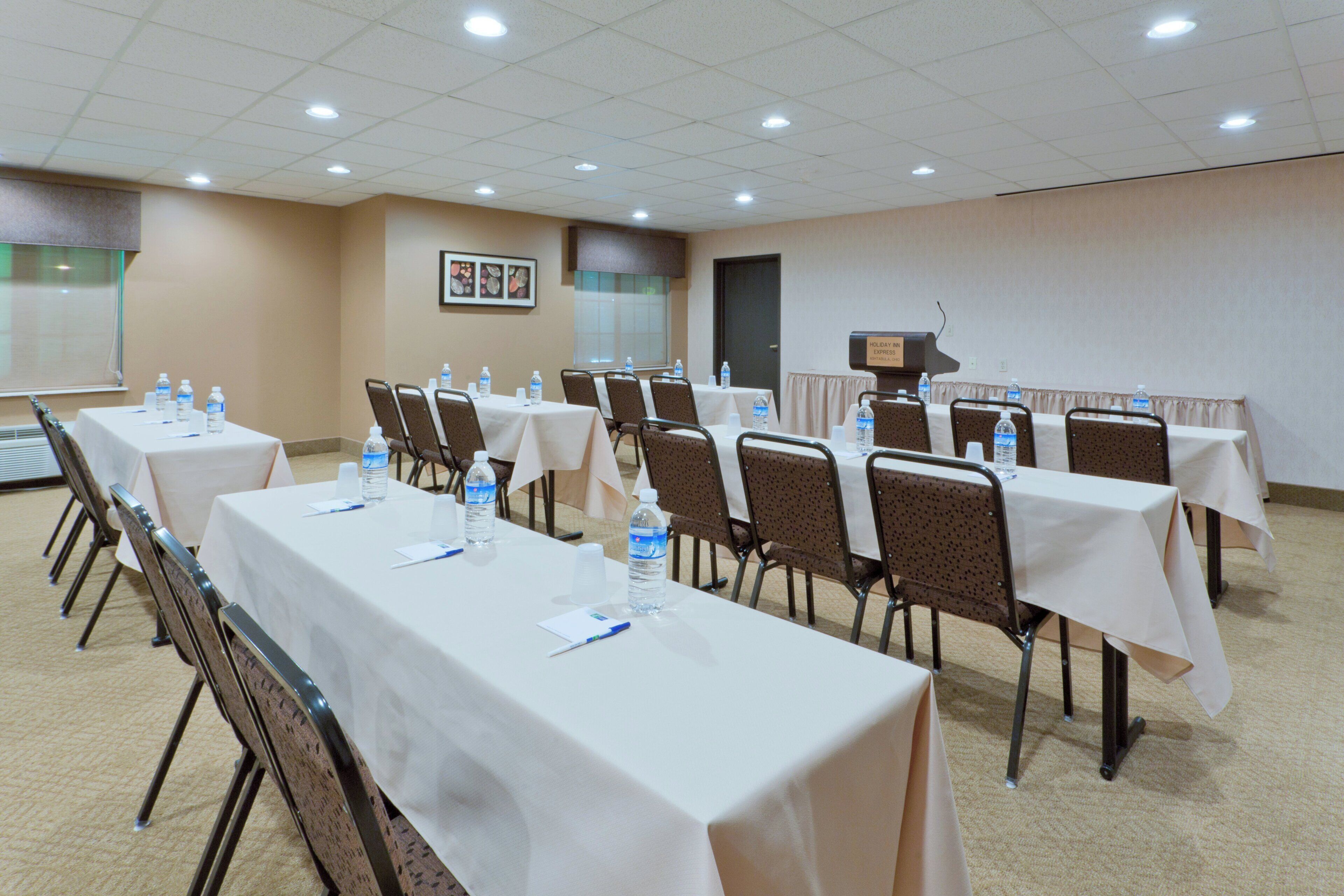 Una sala conferenze con tavoli apparecchiati per riunioni, dotata di bottiglie d'acqua e cartellini con i nomi.