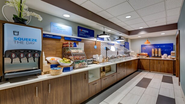 A breakfast bar with a fruit bowl, cereal, and a water dispenser. - Holiday Inn Express Hotel & Suites Ashtabula-Geneva by IHG (Austinburg)