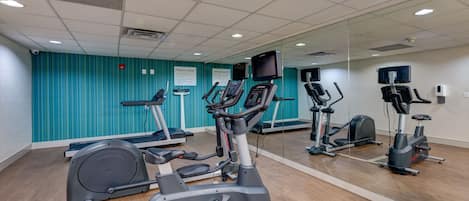 Een fitnessruimte met diverse trainingsapparaten, waaronder loopbanden, een elliptische trainer en een hometrainer.