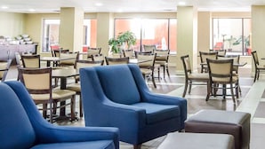 A spacious dining area with multiple tables and chairs, a kitchenette in the background, and large windows allowing natural light. - Comfort Inn Winchester (Winchester)