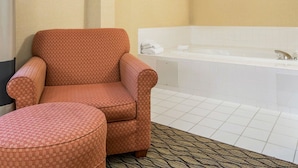 A bathroom with a bathtub, a chair, and a small ottoman. - Comfort Inn Winchester (Winchester)