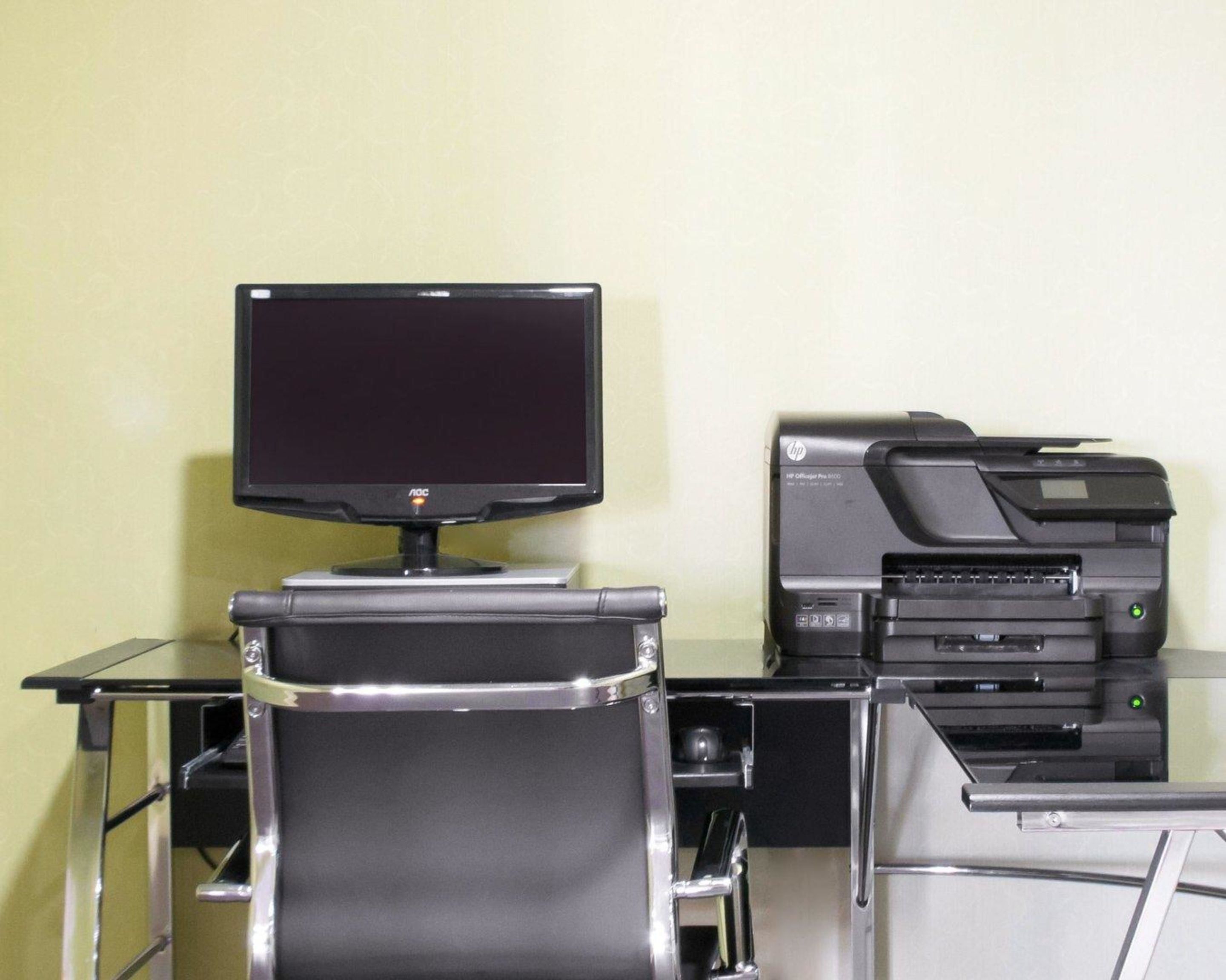 A workspace with a monitor, printer, and chair.