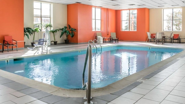 An indoor swimming pool with tiled flooring, orange walls, and potted plants. - Comfort Inn Winchester (Winchester)