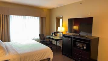 Une chambre d’hôtel équipée d’un lit, d’un bureau, d’une télévision et d’un petit réfrigérateur.