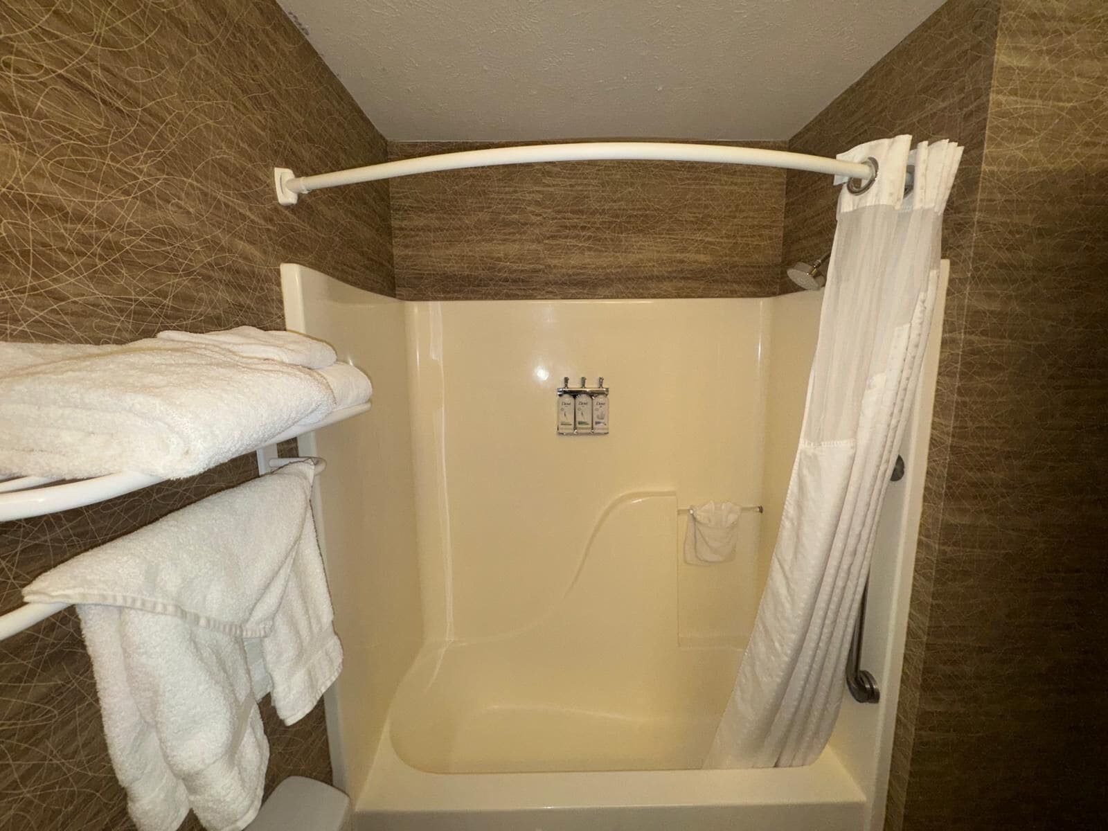 Un baño con bañera, ducha y un perchero con toallas.