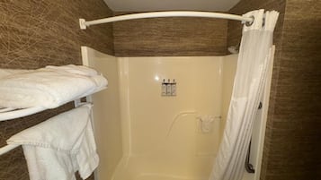 Un baño con bañera, ducha y un perchero con toallas.