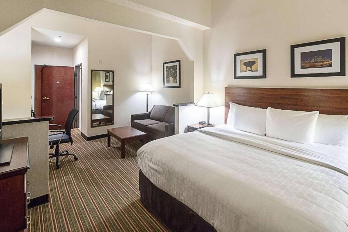 A hotel room with a bed, desk, chair, and a small table.
