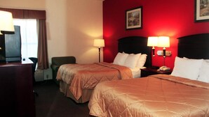A hotel room with two beds, a desk, and a chair. There are two bedside lamps and a telephone on the nightstand. - Truckerz Inn (Jacksonville)