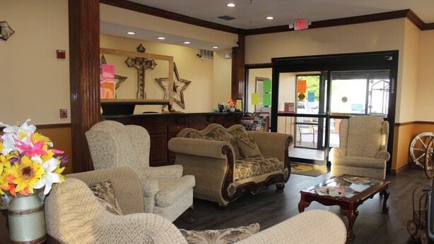 A lobby with a reception desk, patterned sofas, a coffee table, and a decorative wheel. - Truckerz Inn (Jacksonville)