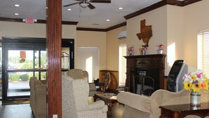 A lobby with a fireplace, seating area, and an exit sign. - Truckerz Inn (Jacksonville)