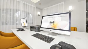 Un bureau moderne avec deux ordinateurs Apple iMac sur un bureau blanc, une imprimante Brother et une chaise jaune.
