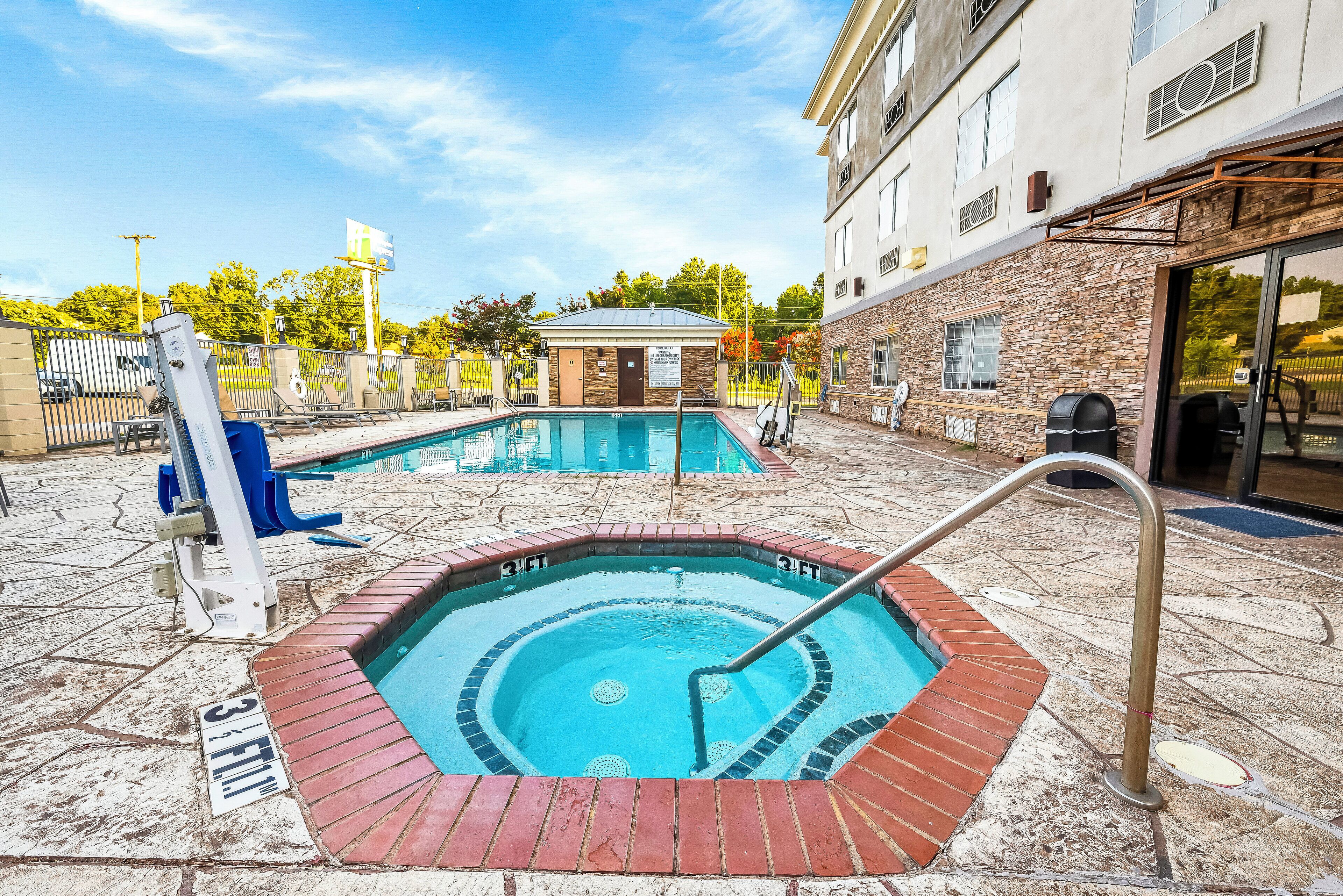A swimming pool with a hot tub, a lifeguard chair, and a covered area.