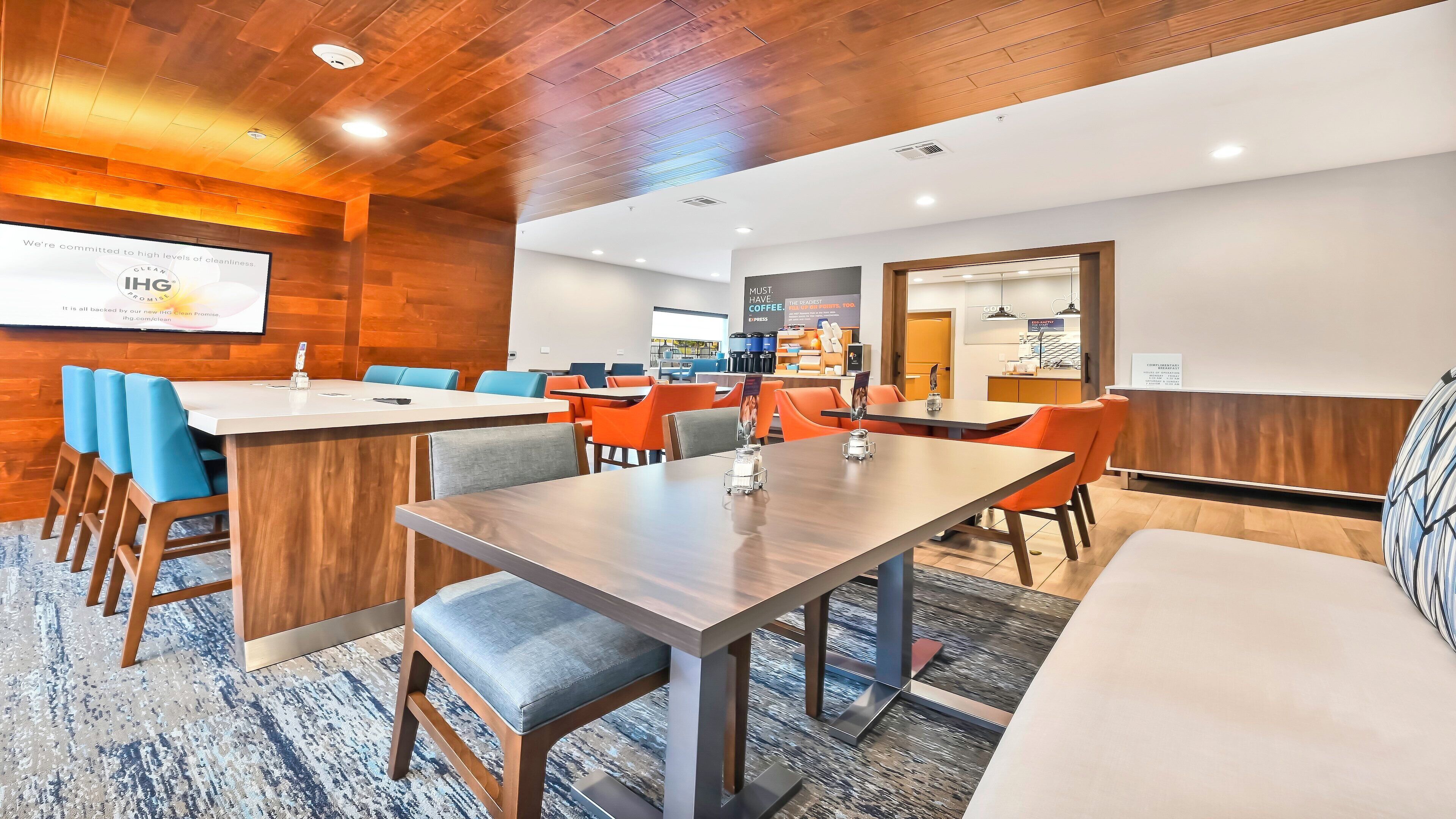 A modern conference room with wooden paneling, a large screen displaying a presentation, and a coffee station in the background.