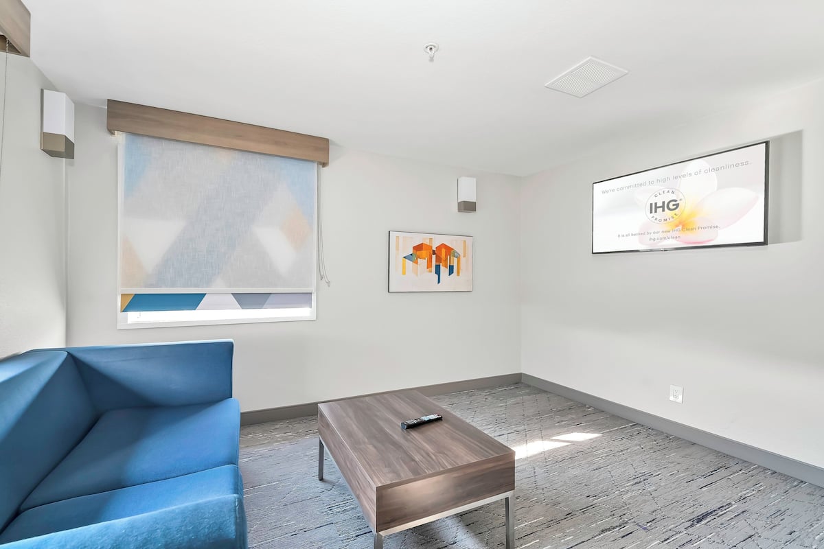 Una habitación moderna y luminosa con una silla azul, una pequeña mesa de madera y una obra de arte enmarcada en la pared.