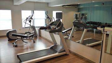 A gym with treadmills, elliptical machines, and free weights.