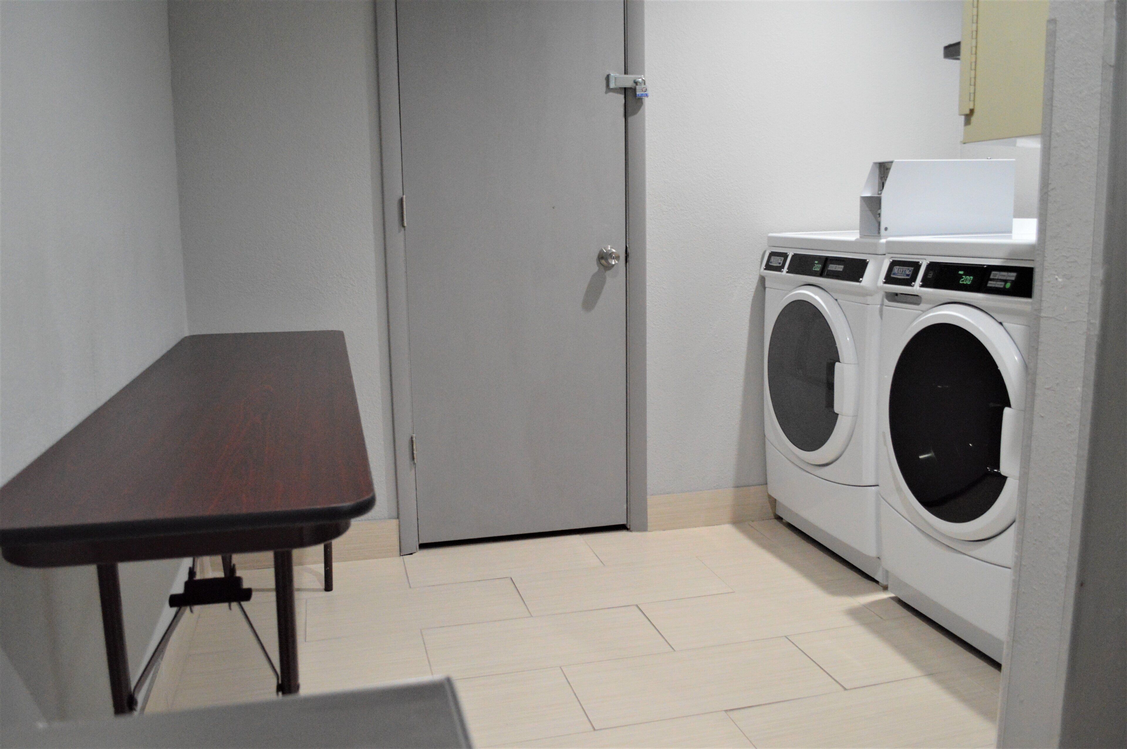 A laundry room with a table and two washing machines.